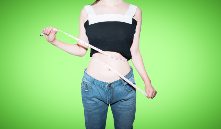 美女拿着皮尺卷尺测量自己的腰围减肥概念