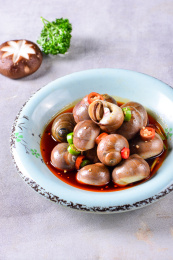 一盘凉拌红油玉螺凉菜放在灰色底板上