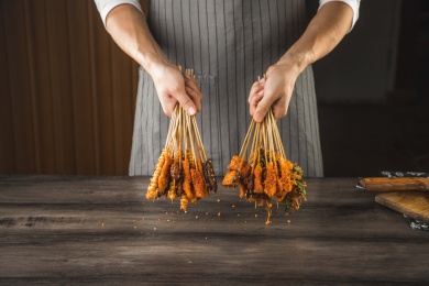 一位厨师在桌子前双手拿着油炸小串