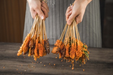 一位厨师在桌子前双手拿着油炸小串