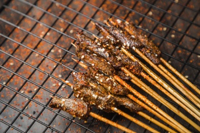 黑色烤架上放着几串撒着辣椒面的油炸牛肉小串