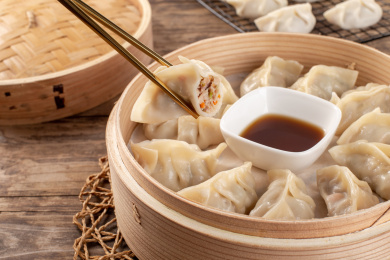 满满一笼蒸饺上筷子夹起露出肉馅的手工蒸饺