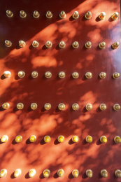 光影下的红色宫门上镶嵌着金黄色的门钉