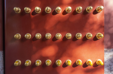 光影下的红色宫门上镶嵌着金黄色的门钉