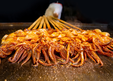 正在铁板上烤制的中国传统美食香辣烤鱿鱼