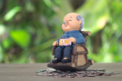 放在一堆美元硬币上坐着摇椅的老爷爷模型