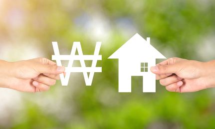 一只手拿着韩元货币符号和另一只手拿着小房子做交换