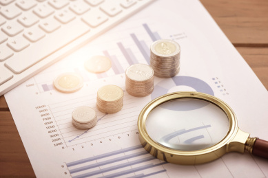 放在财务数据报表上的硬币、放大镜和电脑键盘