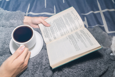 一个人在温暖的被子上看书学习放松喝咖啡喝奶茶