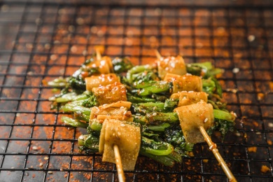 黑色烤架上放着几串撒着辣椒面的油炸干豆腐素串