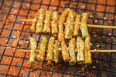 黑色烤架上放着几串撒着辣椒面的油炸豇豆