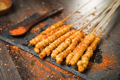 黑色烤架上放着几串撒着辣椒面的油炸苞米粒