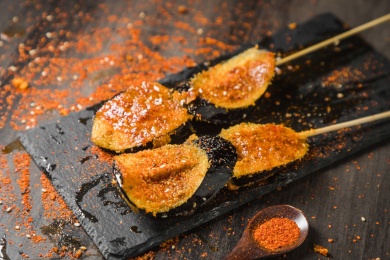 黑色烤架上放着两串撒着辣椒面油炸茄子片