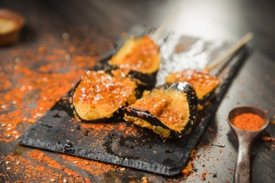 黑色烤架上放着两串撒着辣椒面油炸茄子片