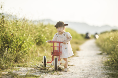 一个可爱的小女孩在田野小路骑自行车