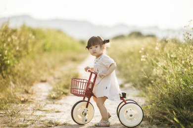 一个可爱的小女孩在田野小路骑自行车