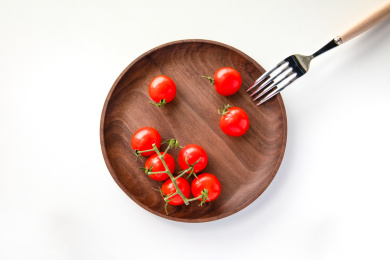 放在木制托盘里的红色小番茄，金属叉子