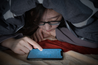 一个人躺在床上躲在被窝里看手机玩手机失眠被蓝光损害眼睛