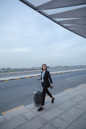 拿着行李箱自信大步向前走的商务女士