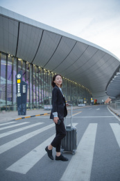 一位商务女士拉着拉杆箱过斑马线