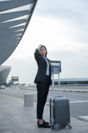 一位身穿正装的女白领带着拉杆箱站在路边