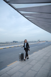 一位商务女士拿着拉杆箱走路