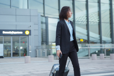 一位身穿正装的女白领拎着拉杆箱过马路