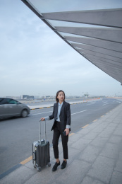 一位商务女士拿着拉杆箱走路