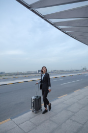 一位商务女士拿着拉杆箱走路