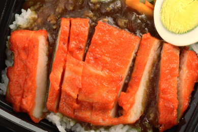 摆放在黑色桌子上的外卖蜜汁鸡排饭