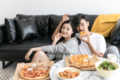 一对情侣温馨地坐在地毯上吃饭
