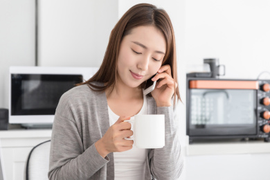 一名年轻女性在家中微笑着打电话