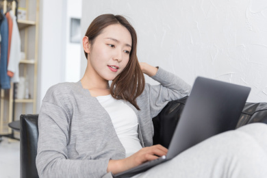 一名年轻女性在沙发上使用笔记本电脑休闲娱乐