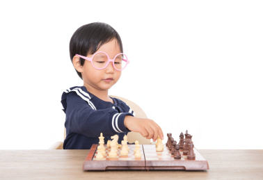 戴着眼镜框的中国小女孩在认真的下国际象棋