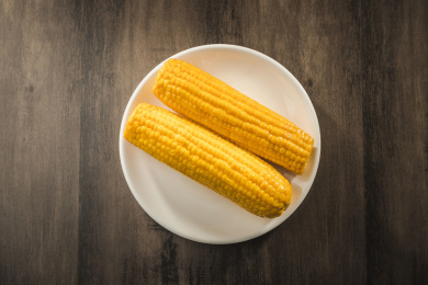 暗色桌面上放着一盘金黄色的水果玉米