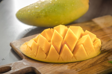 棕色木纹桌面上放着一枚划成网文的芒果