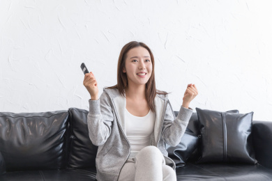 一名年轻女性在沙发上看电视欢呼