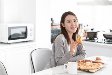 一名年轻女性在餐桌上拿着披萨