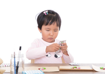 白背景前扮演医药师的小女孩在模拟配药