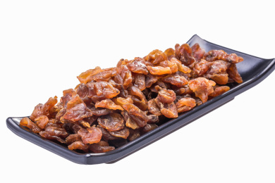 黑色长碟里棕色的干桂圆果肉在白色背景上