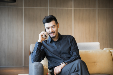 一名商务男士坐在沙发上使用手机打电话