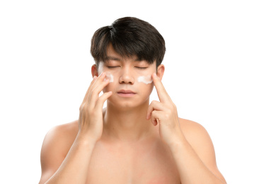  白色背景里的正在涂抹洗面奶的亚洲男士面部特写，化妆护肤整容