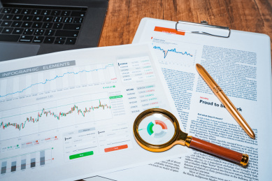 办公室内办公桌面上放着放大镜以及图表报表办公概念