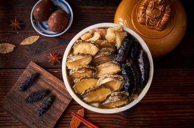 木纹背景上陶瓷餐具中摆放的佛跳墙