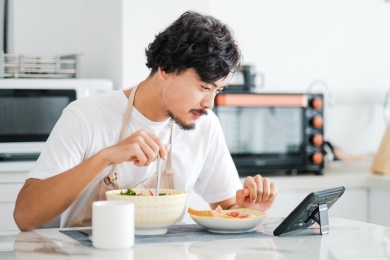 年轻男人在家里一边吃早饭一边看平板电脑