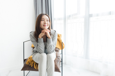 一个年轻女性在客厅坐在沙发椅上微笑看向窗外