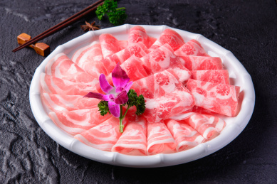放在黑色水泥板上白色圆盘装的雪花牛肉卷