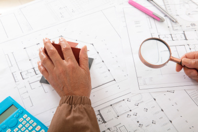 建筑工程师手摸图纸上的房屋模型另一只手拿放大镜观察图纸