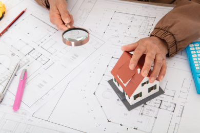 建筑工程师手摸图纸上的房屋模型另一只手拿放大镜观察图纸