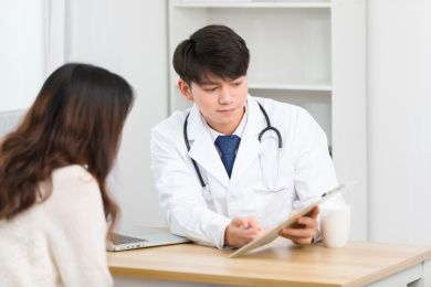 坐在办公室里的亚洲男医生正在询问患者的病情